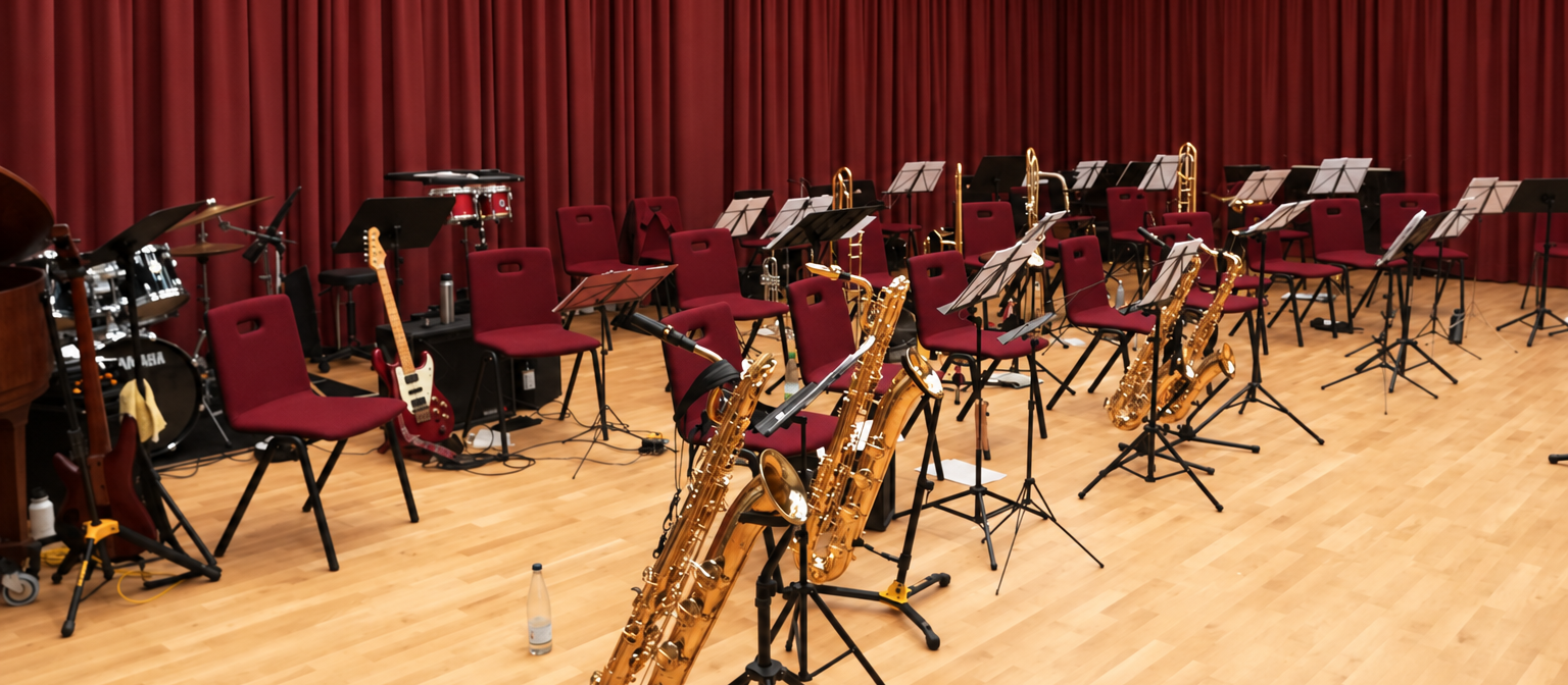 Big-Band-Aufbau mit Instrumenten, Notenständern und rotem Vorhang